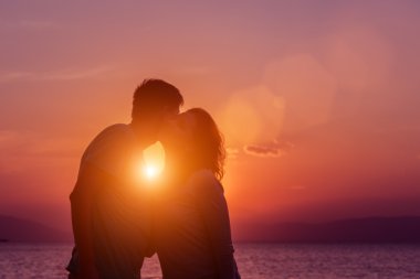 Genç çift sahilde günbatımı ayakta zevk.