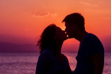 Genç çift sahilde günbatımı ayakta zevk.