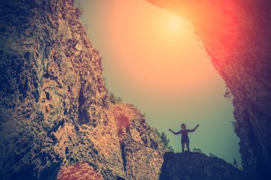 Gökyüzü mağara yakınındaki bir kayanın üzerinde duran bir kadın silüeti