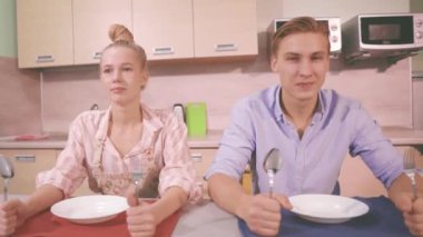 Genç bir kadın ve bir erkek mutfakta hareketsiz otururlar.