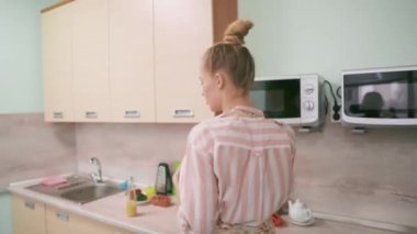 Genç kadın kocasını mutfakta yanağından öpüyor..