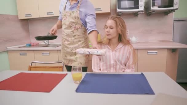 Чоловік кладе сковороду з яйцями перед своєю дружиною — стокове відео