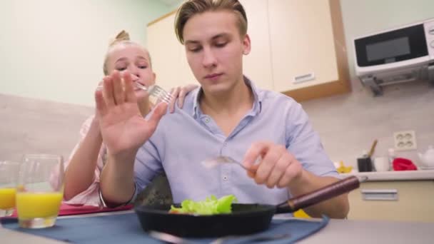 Женщина пытается взять еду из сковородки своего мужа — стоковое видео