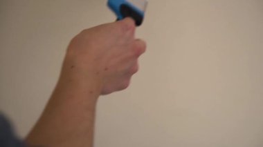 Adam dalgalı bir çizgi çiziyor. Duvarında beyaz boya olan bir fırça.