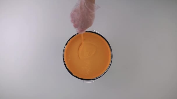 남자가 오렌지 페인트를 막대와 섞는다 위에서 카메라 — 비디오