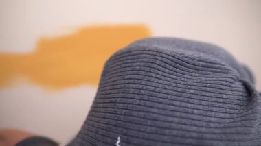 Bir işçi turuncu bir duvar boyunca boya fırçası kullanıyor. Yatay ve dikey çerçeve