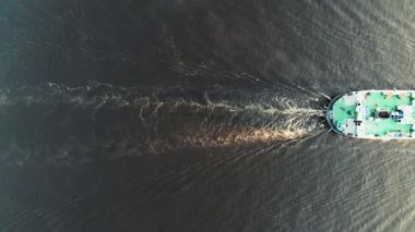 Kargo taşıyan nehir taşımacılığı nehir boyunca yüzer ve suda iz bırakır. Yukarıdan bak. Minimalist. Helikopterden ateş ediliyor.