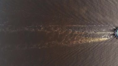 Nehir taşımacılığının bir kısmı nehirde yüzüyor. Gemiden gelen suyun üzerinde iz var. Yukarıdan bak. Minimalist. Helikopterden ateş ediliyor.