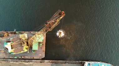 Tarayıcı nehrin dibindeki kumu kaldırıyor ve asfaltsız bir gemiye döküyor. Nehrin dibinden kum topluyorum. Helikopterden ateş ediliyor.