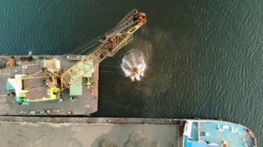 Tarayıcı nehrin dibindeki kumu kaldırıyor ve asfaltsız bir gemiye döküyor. Yukarıdan bak. Nehrin dibinden kum topluyorum. Helikopterden ateş ediliyor.