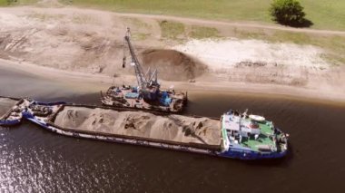 Kılavuz, gemiden sahile kum boşaltıyor. Kum toplama ve taşıma. Helikopterden ateş ediliyor.