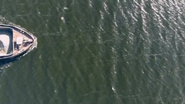 Bir çöp teknesi nehrin aşağısına kum taşır. Yukarıdan bak. Bir yığın kum. Helikopterden ateş ediliyor.