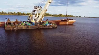 Dredger nehrin dibindeki kumu kaldırıyor. Su deposunun dibindeki toprağın çıkarılması ve kazılması. Güneşli bir gün. Helikopterden ateş ediliyor.