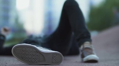 Adam kaykayın üzerinde yatıyor. Bir kaykay buradan geçiyor. Yeni nesil. Olağanüstü bir spor. Kaykay.