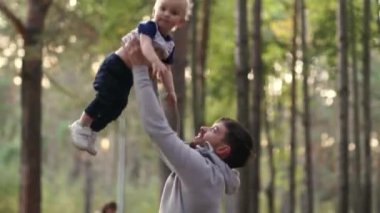 Bir adam oğlunu fırlatır ve mutlu bir şekilde güler. Parkta bir çocukla yürümek. Çocuklarla oyunlar. Mutlu bir aile.