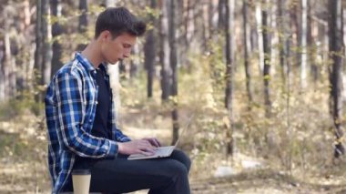 Adam bir fincan kahveyle parkta otururken dizüstü bilgisayarın başında çalışıyor. Uzaktan kumanda. Serbest çalışıyorum. Rahat bir iş yeri