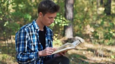 Genç adam güneşli bir günde parkta otururken bir kitap okur. Keyifli zaman geçirme. Parkta dinlen. Açık havada kitap okuyorum.