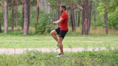 Ormanda koşmadan önce ısınma turu yapan bir adam. Yavaş çekim.