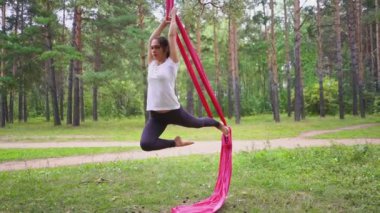 Ormanın ortasında Asya 'da yoga hamağında asılı bir kadın. Açık hava sporları