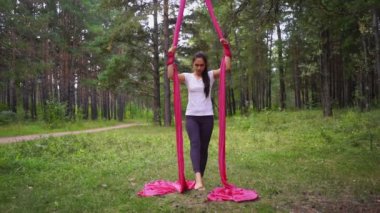 Kadın baş aşağı yoga hamağını tutuyor. Açık hava sporları