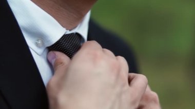 Takım elbiseli bir adam kravatını boynuna dolamış. Yakın plan.