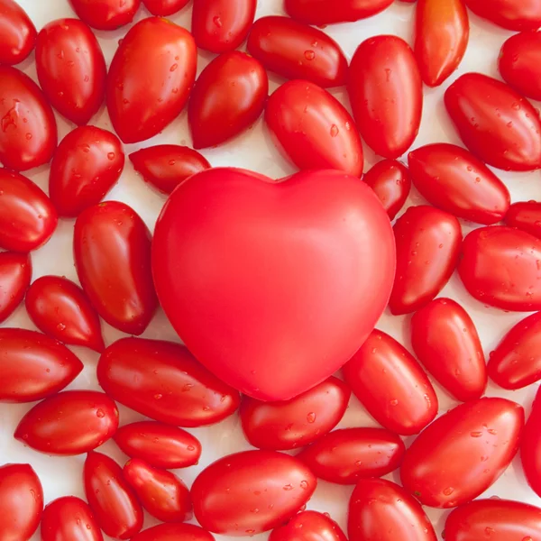 Coração de plástico e tomate cereja — Fotografia de Stock