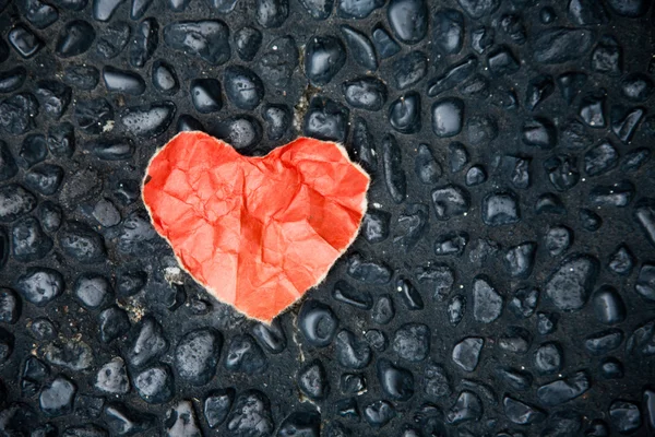 Corazón de papel rojo en el suelo de piedra de guijarro — Foto de Stock