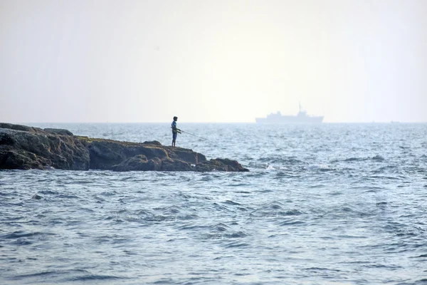 Мальчик-рыбак и большой корабль — стоковое фото