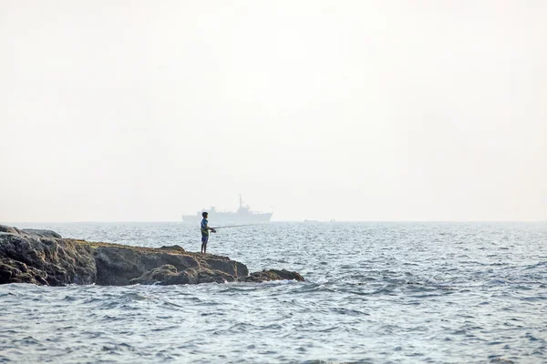 Ragazzo pescatore e una grande nave — Foto Stock