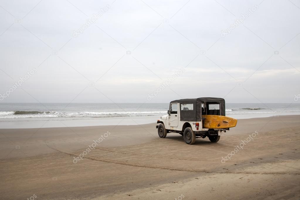 Car with surfboard on the beach.