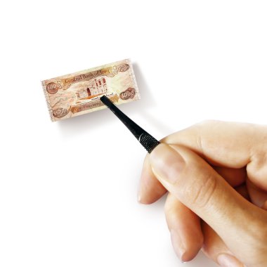 küçük banknot tutan bir pincet ile el