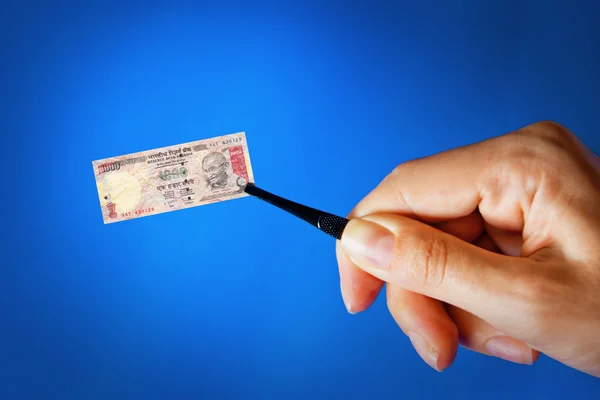 Mano con una pinza que sostiene un billete pequeño —  Fotos de Stock