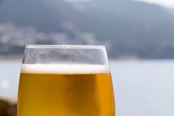 Sklenice piva s mořem v pozadí — Stock fotografie