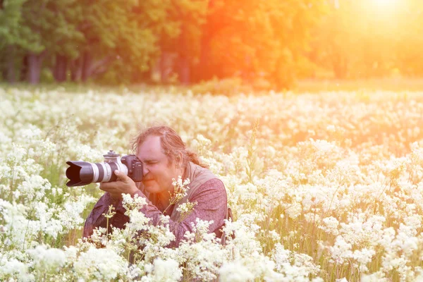 Photographer with camera on flower field — Stock Photo, Image