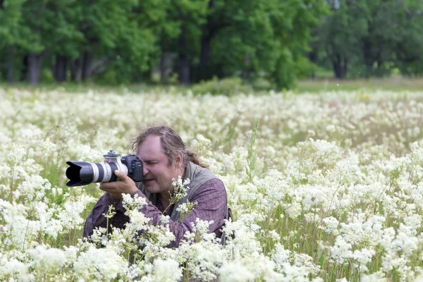 Fotógrafo con cámara en el campo de flores —  Fotos de Stock