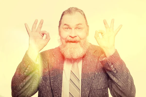 Bebaarde grappige man in grijze jas vertoont "Oke" — Stockfoto