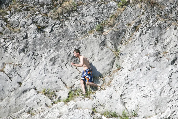 Jeune homme posant sur la roche grise — Photo