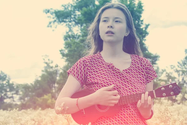 Flickan på ängen med ukulele — Stockfoto