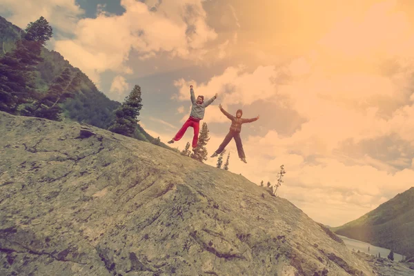 Couple of tourists jumping on rock — Stock fotografie