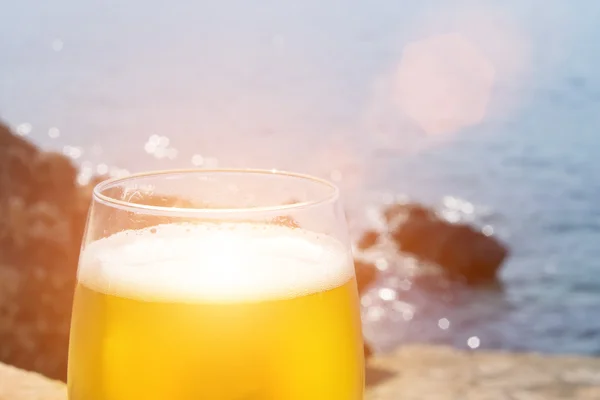 Стакан пива с морем на заднем плане — стоковое фото