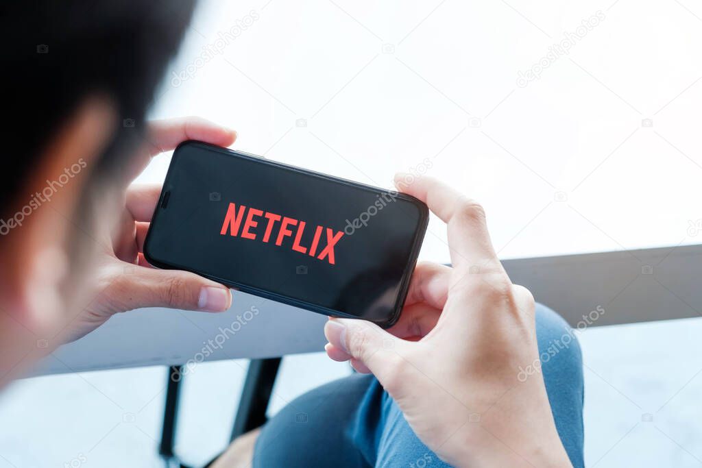 CHIANG MAI, THAILAND,  JAN 17 2021: man hand holding Smart Phone with Netflix logo on Apple iPhone Xs. Netflix is a global provider of streaming movies and TV series