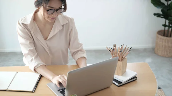 Focused woman journalist freelancer working online on laptop, sitting at desk at home, looking at screen, typing, serious young female writing blog or chatting with friends in social networ