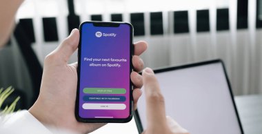 CHIANG MAI, THAILAND - 28 JUL 2020: Ekranda Spotify logosu olan yepyeni bir Apple iPhone XS tutan kişi. Spotify popüler bir ticari müzik yayın servisidir..