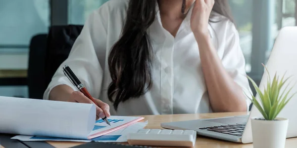 Närbild av affärskvinna eller revisor hand hålla penna arbetar på bärbar dator för att beräkna affärsuppgifter, redovisning dokument och miniräknare på kontoret, affärsidé — Stockfoto