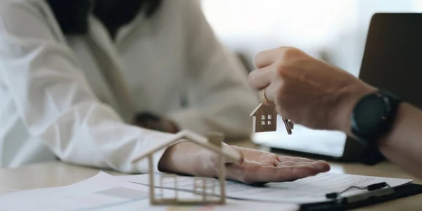 stock image real estate agent holding house key to his client after signing contract agreement in office,concept for real estate, moving home or renting propert