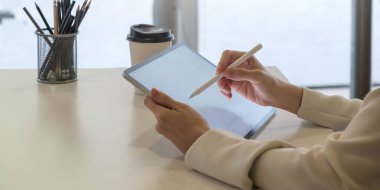 Ofis masasında dijital tablet ve stilus kalem tutan bir kadın var. Ürün görüntüleme kurgusu için boş ekran