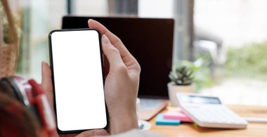 Model resmi boş beyaz ekran cep telefonu. Kadınlar el ele mesajlaşırken evdeki ofiste cep telefonunu kullanıyor.