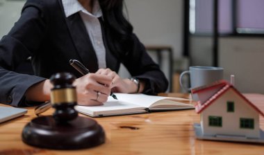Gayrimenkul hukuku kavramı. Gavel, mahkeme salonunda elinde kadın yargıç ile sigorta tazminatı için çalışıyor. Davayı modern ofiste masaya yatırın.