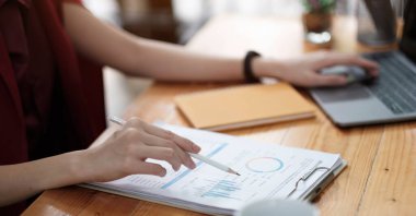 Asyalı erkek finans personeli, şirketin bu yıl hızla büyüyen bar grafiğindeki performansını açıklıyor. Patronuna. Ofisteki masada, mali müşavir.