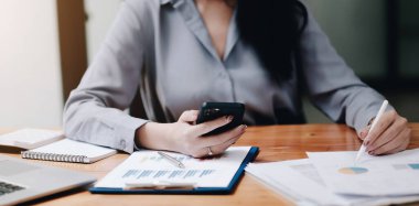 Akıllı telefon ve dizüstü bilgisayar kullanan kadınlara bakış açısını kapat. Analiz edilen mali durum, iş belgesi, grafik ve grafik kağıdı, pazarlama raporu, muhasebe, yatırımcı, ev kavramından çalışma